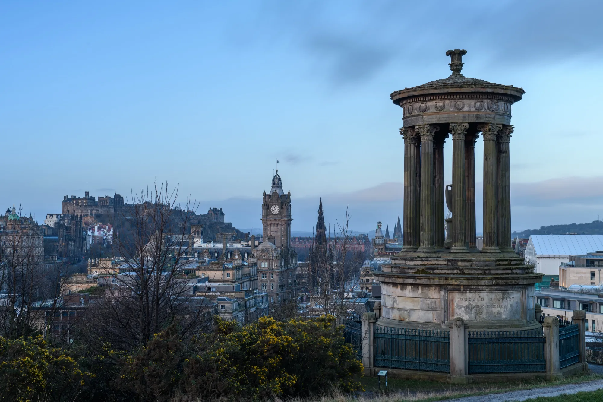 Edinburgh at dusk from Calton Hill, with the castle and the clock tower behind a columned monument