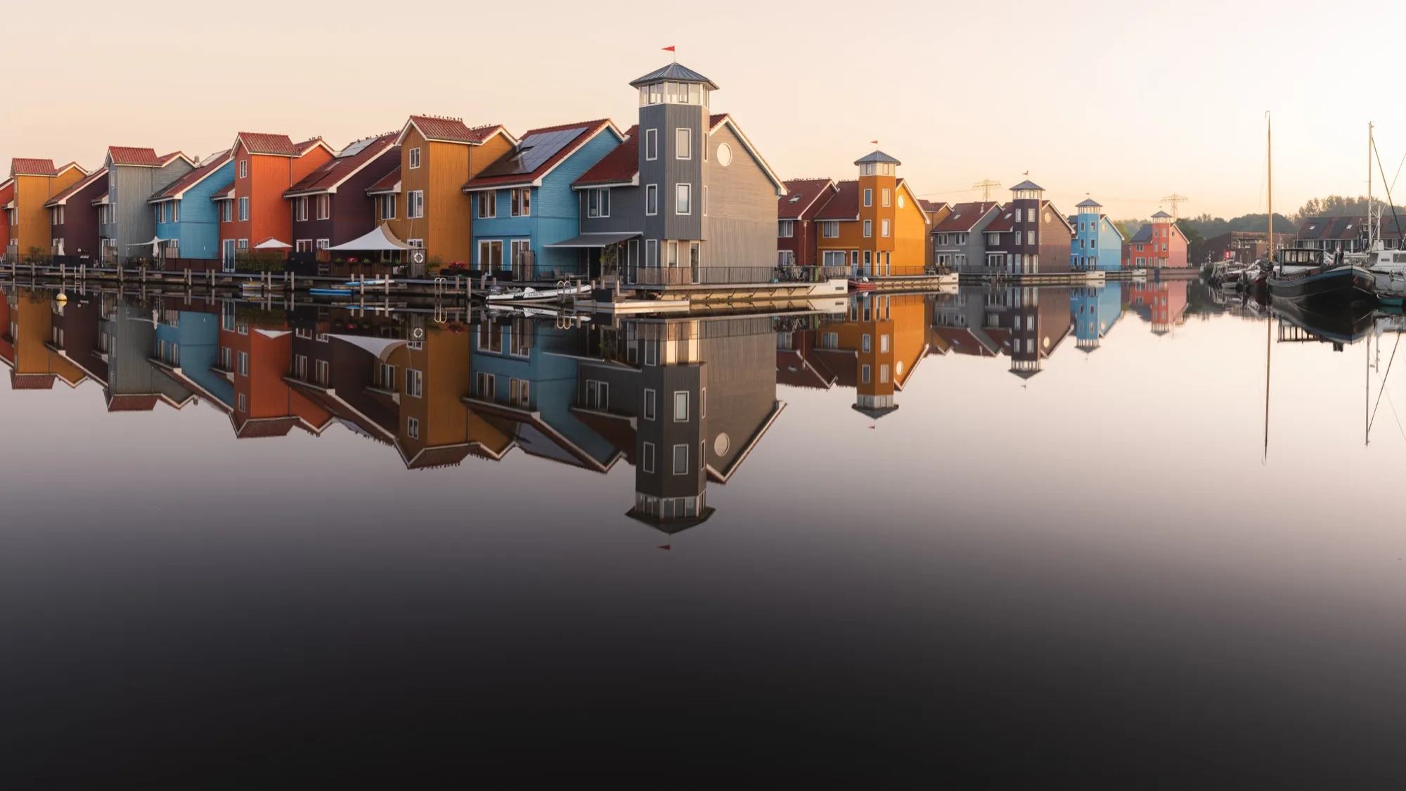 Colourful wooden harbour houses mirrored in still water at sunrise