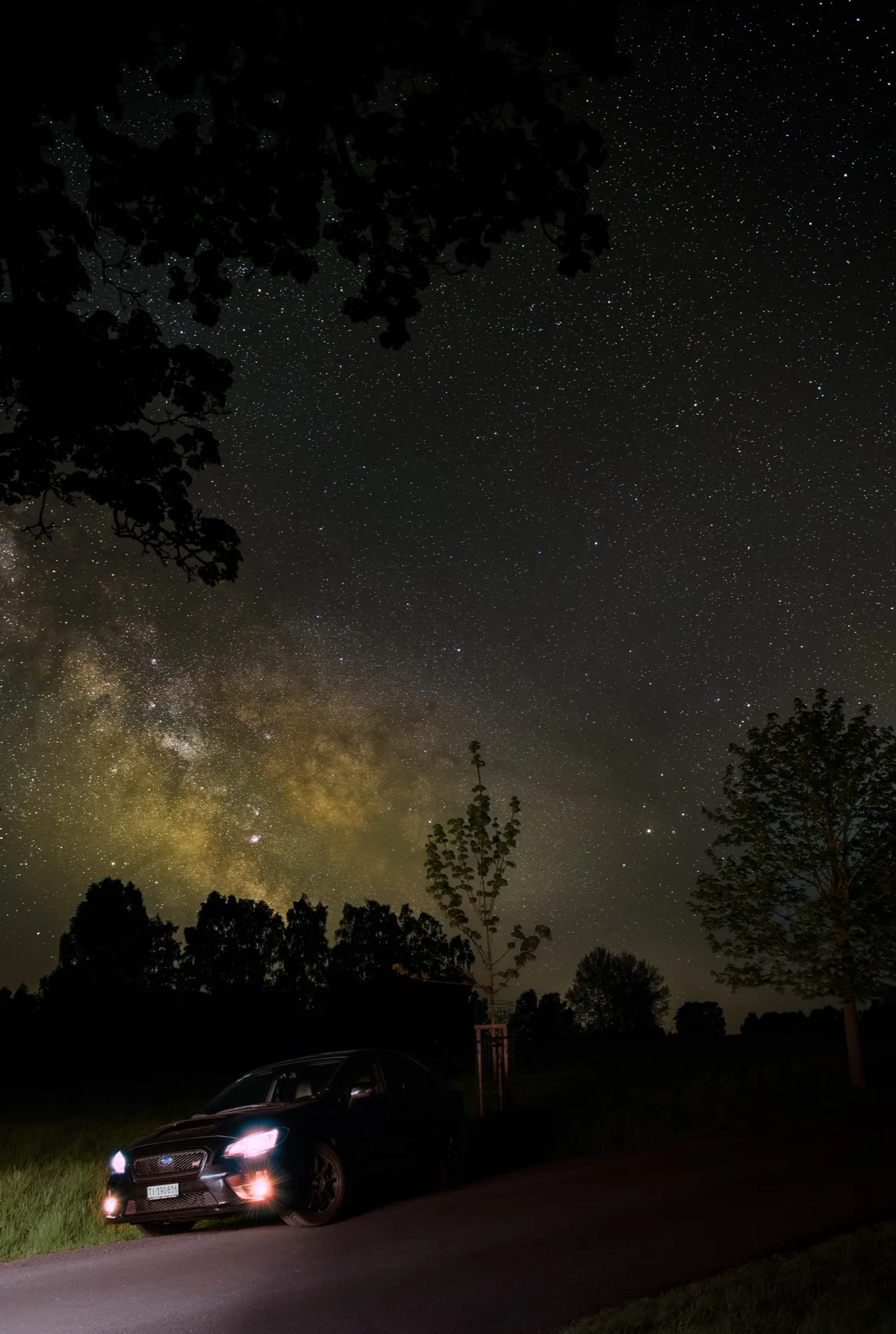 A car on a country road at night under the Milky Way